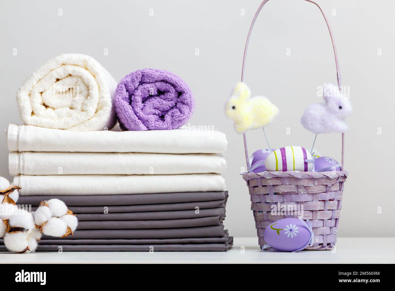 Una pila di lenzuola, un lenzuolo di asciugamani con un ramo di cotone e un decor pasquale Foto Stock