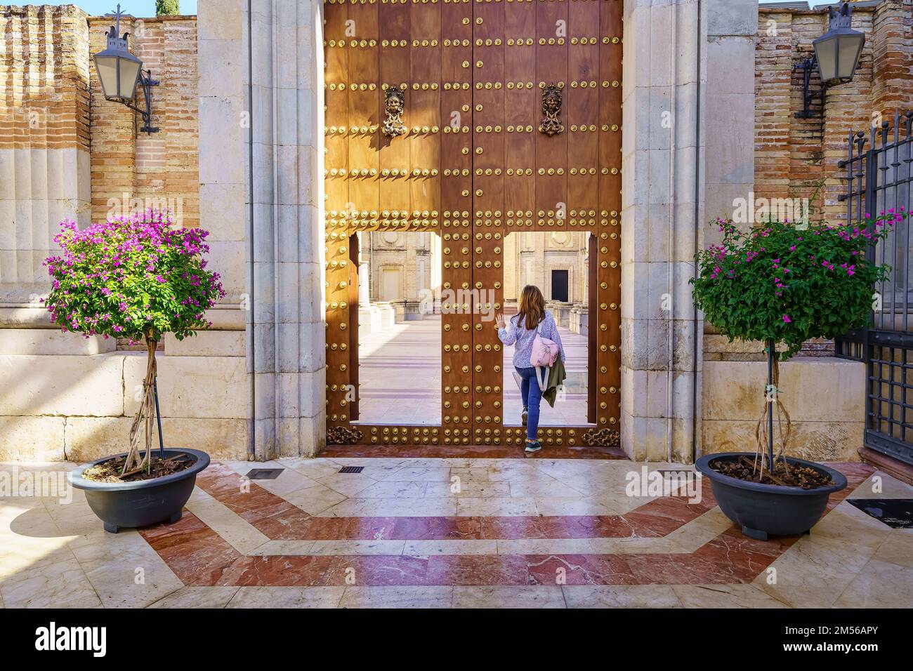 Donna che entra nei terreni della chiesa di San Juan nella città monumentale di Ecija a Siviglia, Spagna. Foto Stock