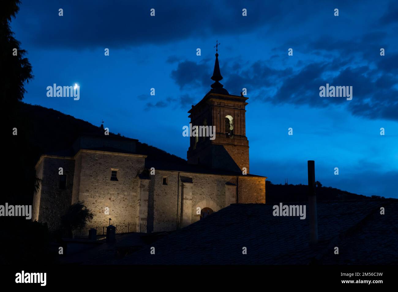 Una luna crescente cerante sorge su Iglesia de San Nicolás de Bari in Molinaseca, León, Spagna. Il paese si trova lungo il Camino Frances, una tipica capra Foto Stock