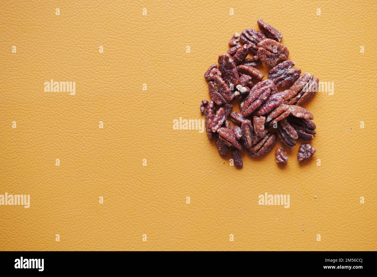 Gustose noci pecan su un asse di legno su un tavolo di colore arancione Foto Stock