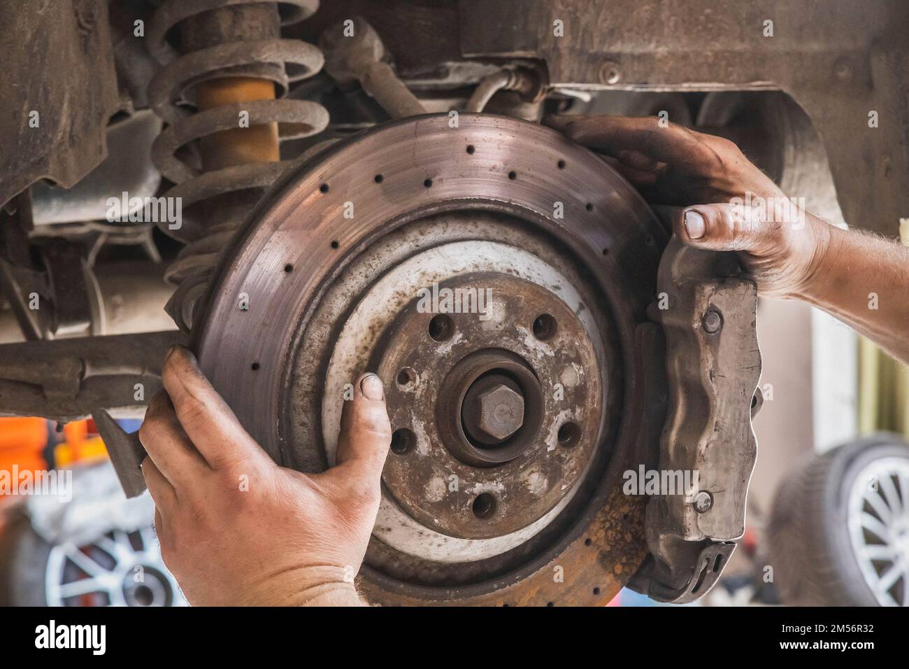 mani sporche lavoratori che cambiano i freni di un'auto in officina Foto Stock