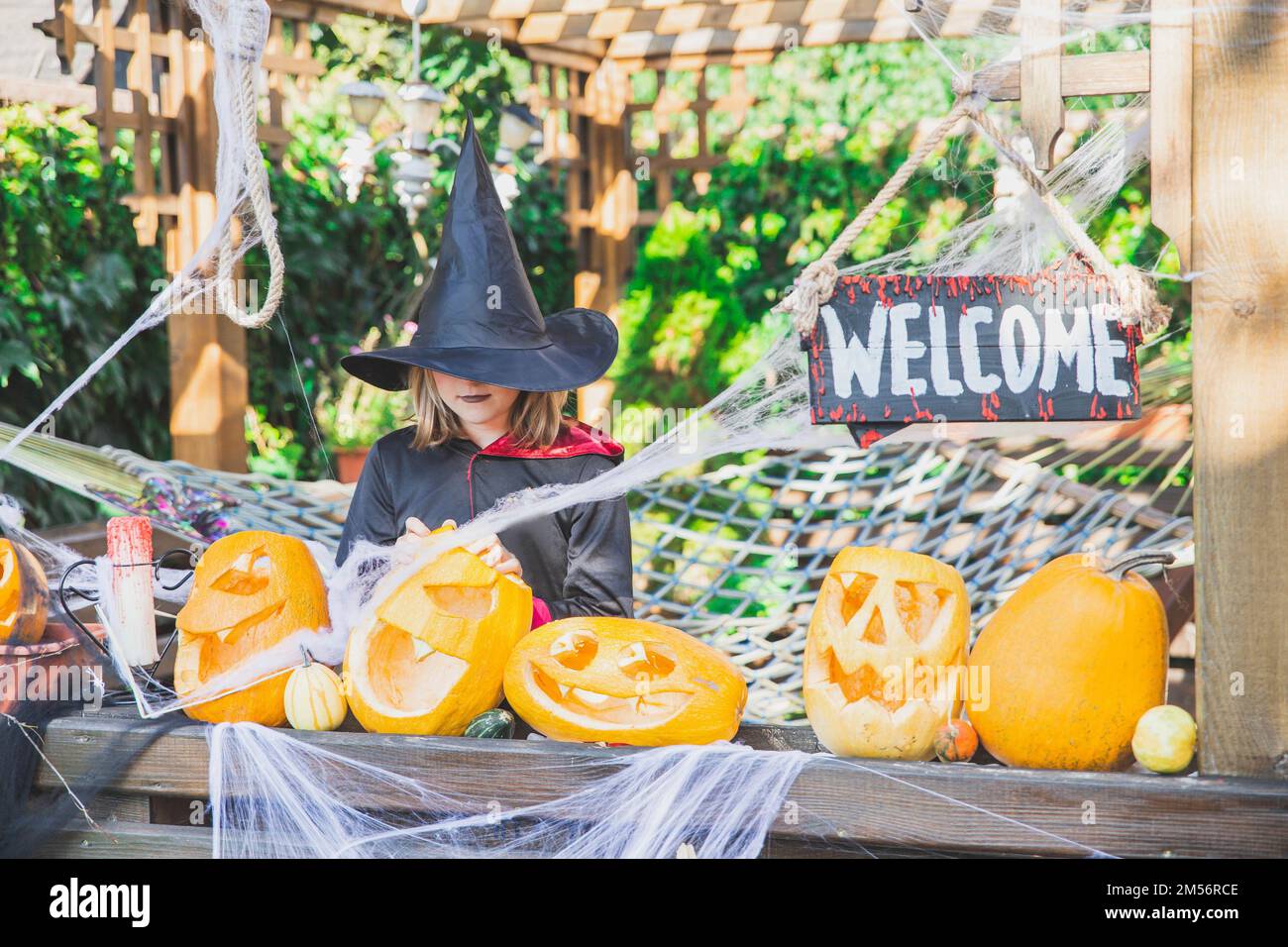 Ragazza in un mantello e un cappello si trova vicino alle zucche di Halloween Foto Stock