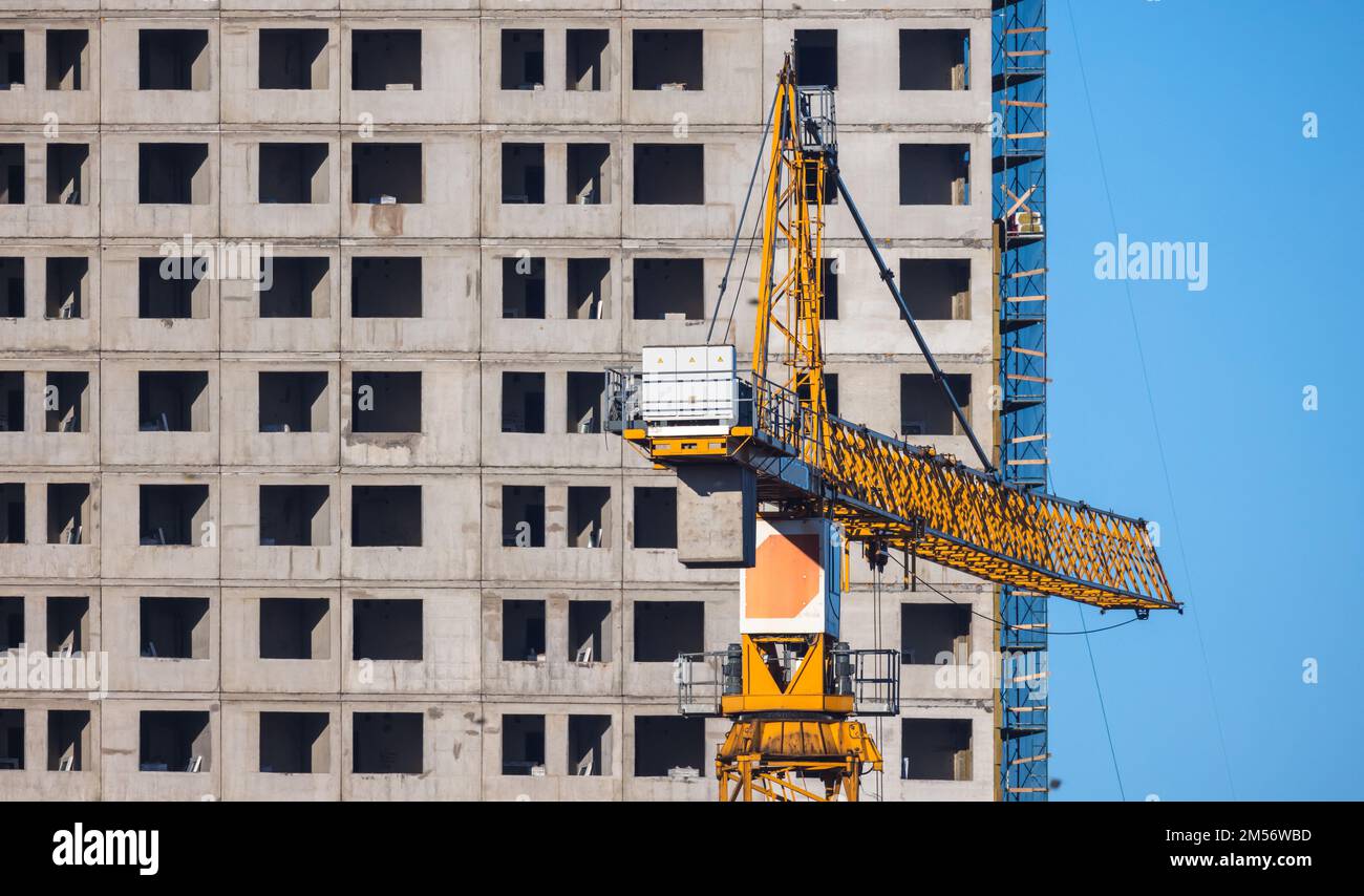 Gru gialla e nuova casa in cemento in costruzione in una giornata di sole Foto Stock