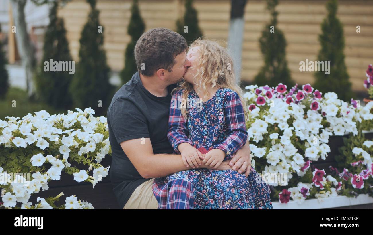 Un ritratto di un padre con la sua figlia in giardino su uno sfondo di petunia bianca. Foto Stock