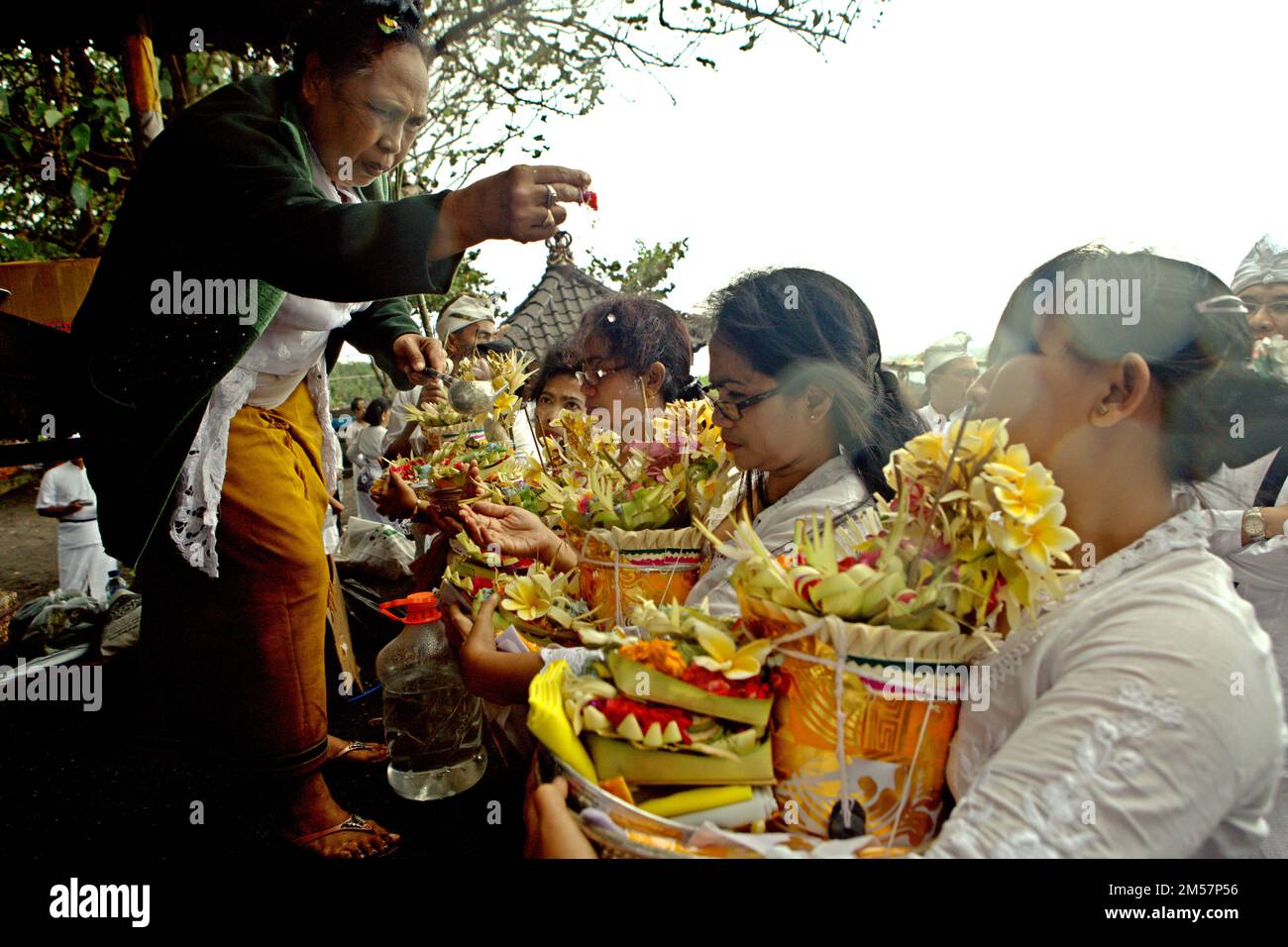 Un sacerdote sta spruzzando l'acqua durante un rituale tenuto da un clan balinese, compresi i membri che provengono dall'isola di Giava, in cui onorano e purificano gli spiriti dei loro ultimi membri della famiglia, su una spiaggia vicino al tempio di Goa Lawah a Dawan, Klungkung, Bali, Indonesia. La religione è vista come 'l'ultima fortezza' del turismo culturale di Bali, secondo un team di scienziati guidati da Nararya Narottama (Università di Udayana, Bali), nel loro documento presentato nel mese di aprile 2018 Conferenza Internazionale sulle destinazioni del Turismo emergenti tenutasi a Dili, Timor Est, accessibile attraverso ResearchGate. Foto Stock