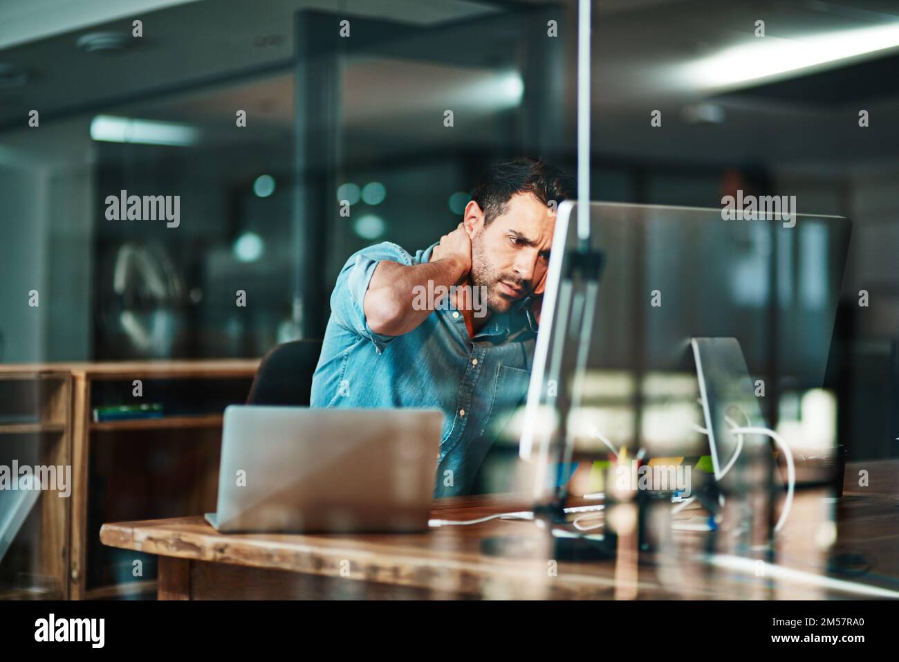 È ancora il giorno. un giovane uomo d'affari che vive stress mentre usa un computer in un ufficio moderno. Foto Stock