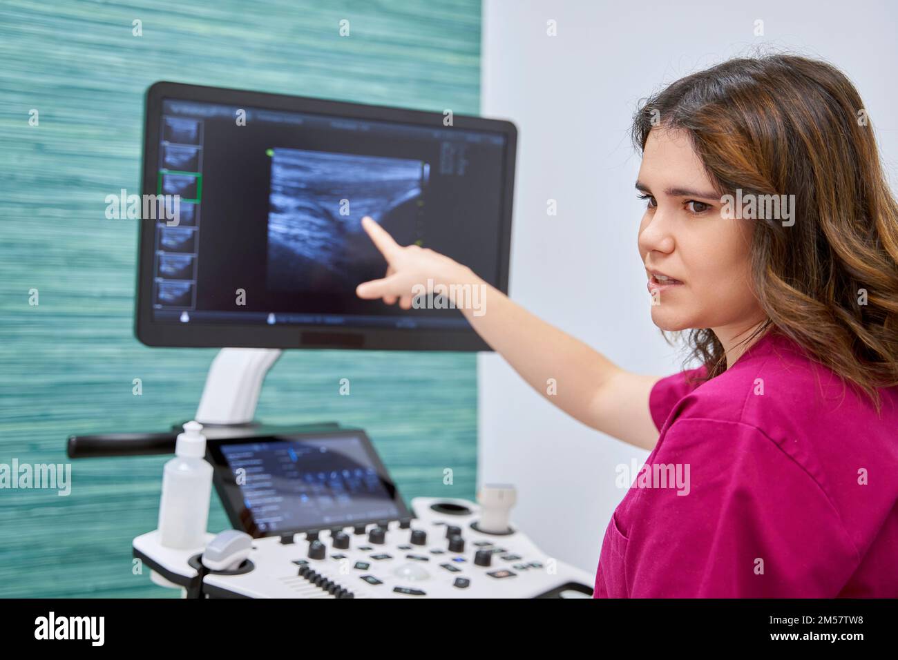 Medico di sesso femminile che indica e mostra qualcosa sull'apparecchiatura a ultrasuoni mentre lavora in un centro medico. Medicina e concetto di salute. Foto Stock