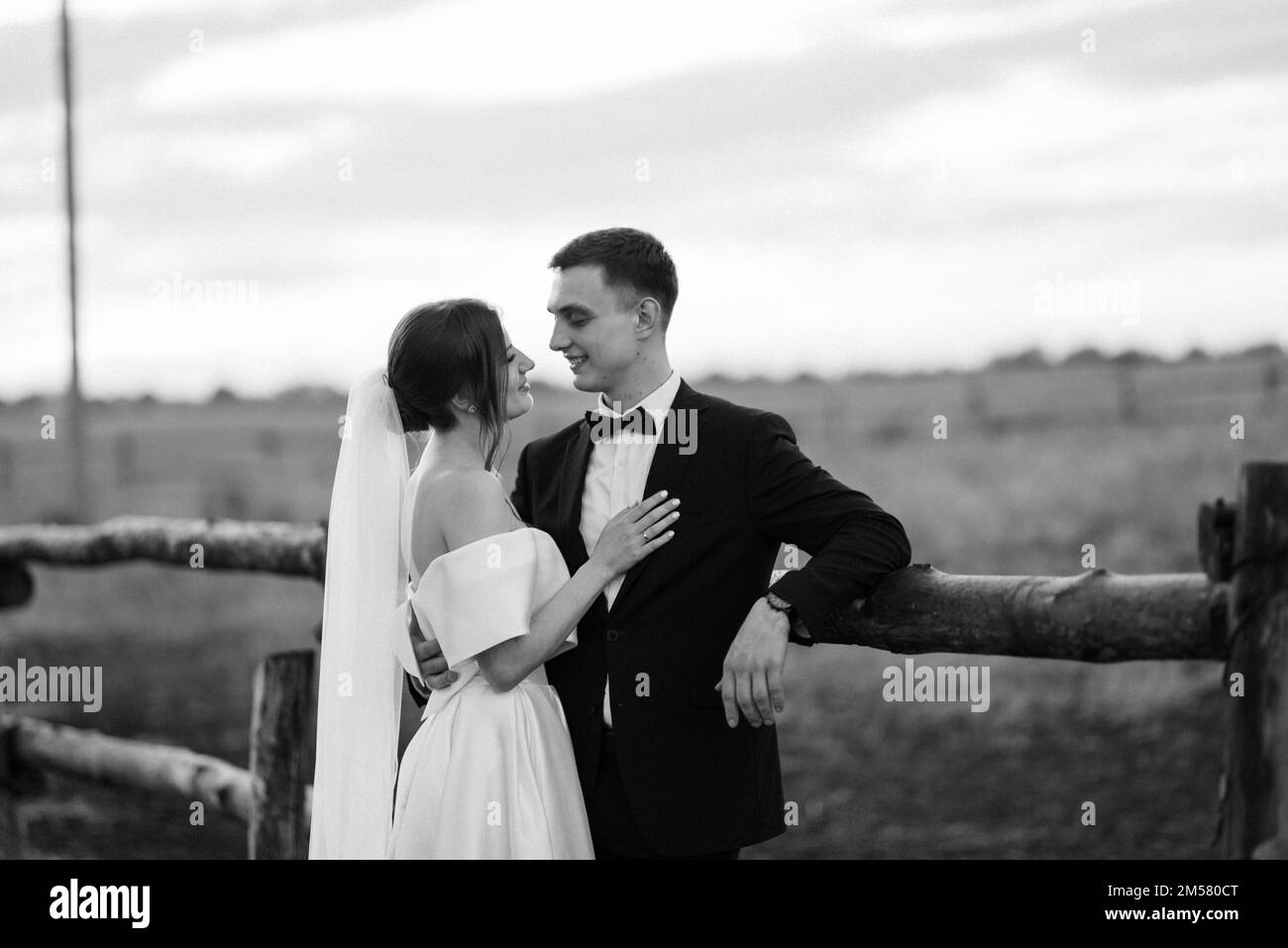 giovane coppia lo sposo in tuta nera e la sposa in un abito corto bianco in  una passeggiata nel villaggio Foto stock - Alamy