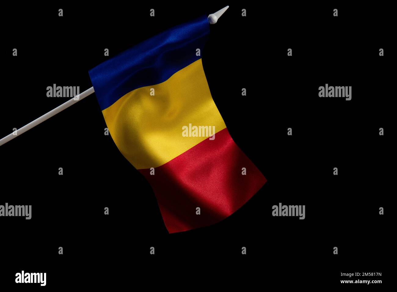 La bandiera rumena su uno sfondo nero che si sviluppa nel vento Foto Stock