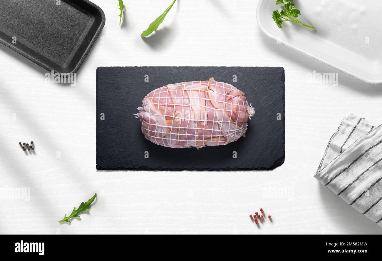 Roti di manzo con pancetta su un piatto di una cucina con vari oggetti dall'alto Foto Stock