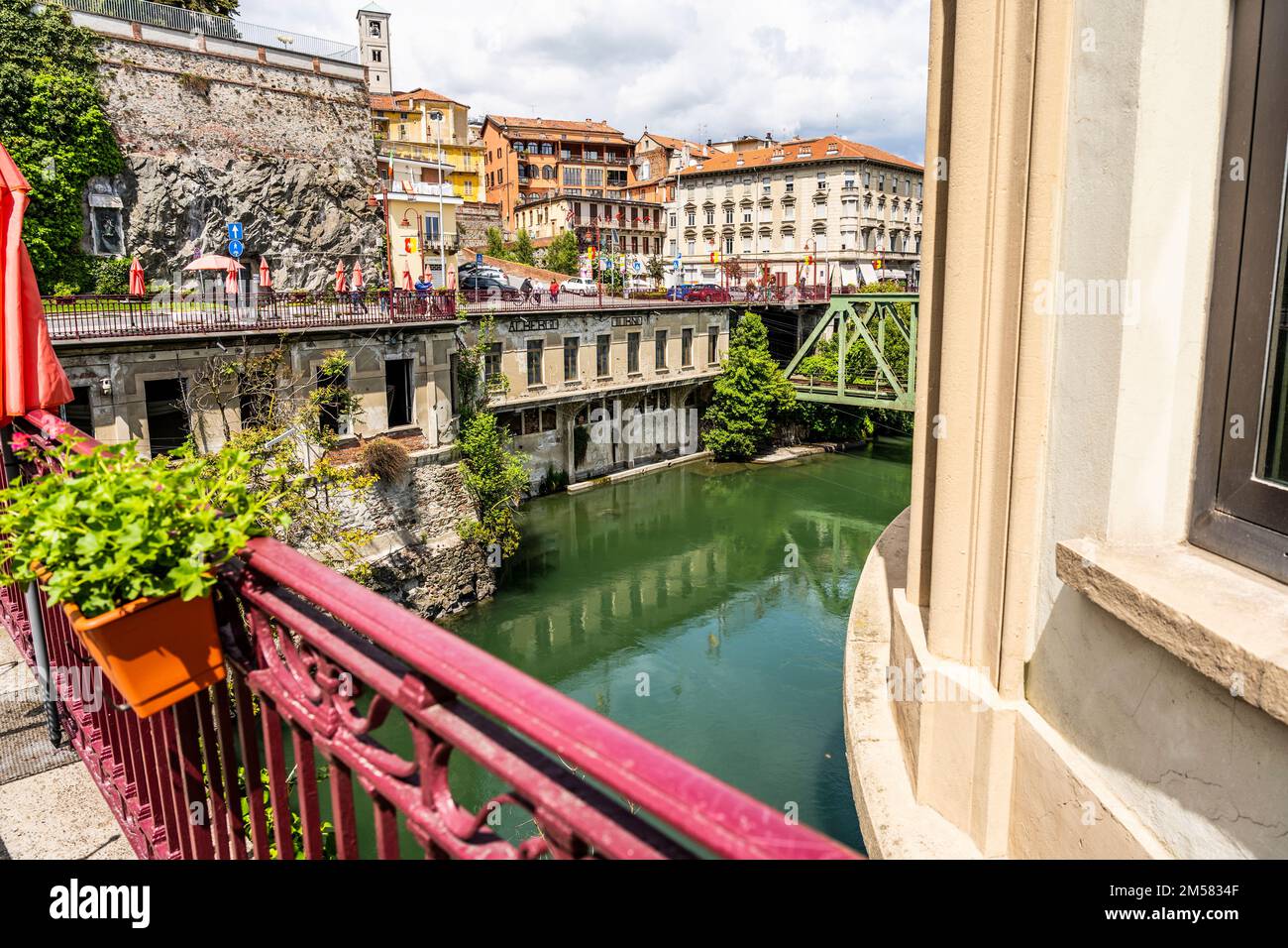 Il fiume Dora Baltea visto da un ponte rosso, con antico hotel abbandonato, a Ivrea, città famosa per il Carnevale, Piemonte, Italia Foto Stock