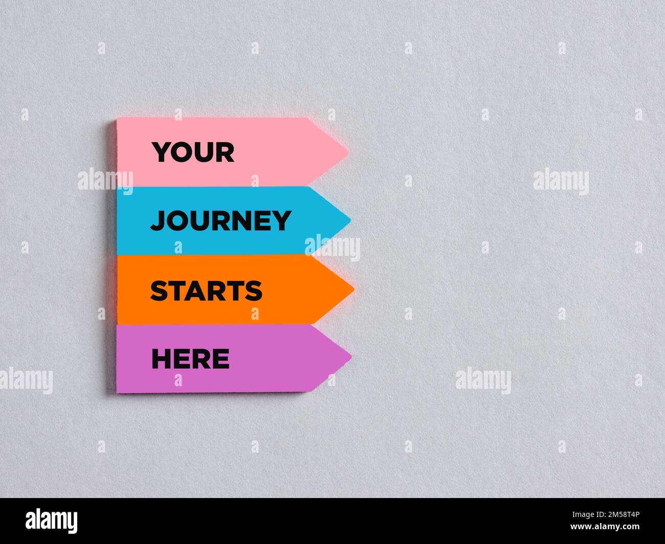 Adesivi colorati a forma di freccia con il messaggio il tuo viaggio inizia qui. Messaggio motivazionale di carriera o stile di vita. Foto Stock