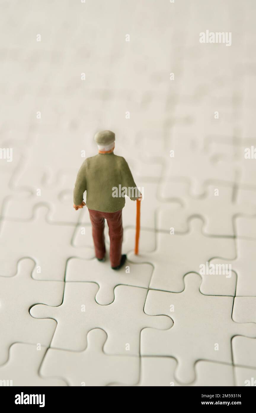 statuetta in miniatura dell'uomo anziano sul puzzle Foto Stock