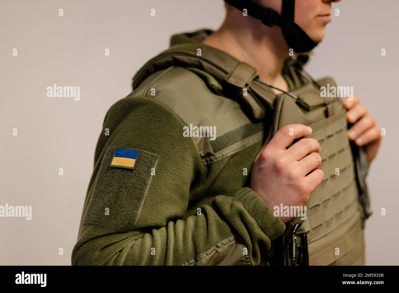 Forze armate dell'Ucraina. Il soldato ucraino si alza e tiene le mani sull'armatura del corpo. Esercito ucraino. Bandiera Ucraina su uniforme militare. Foto Stock