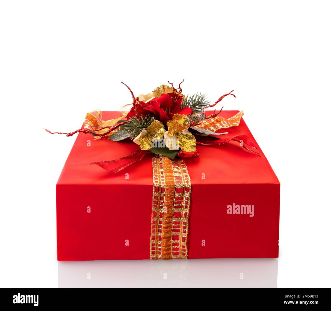 Scatola regalo rossa con fiocco con nastro e fiori falsi in oro e rametti di pino. Regalo di Natale. Isolato su bianco con tracciato di ritaglio, spazio di copia Foto Stock