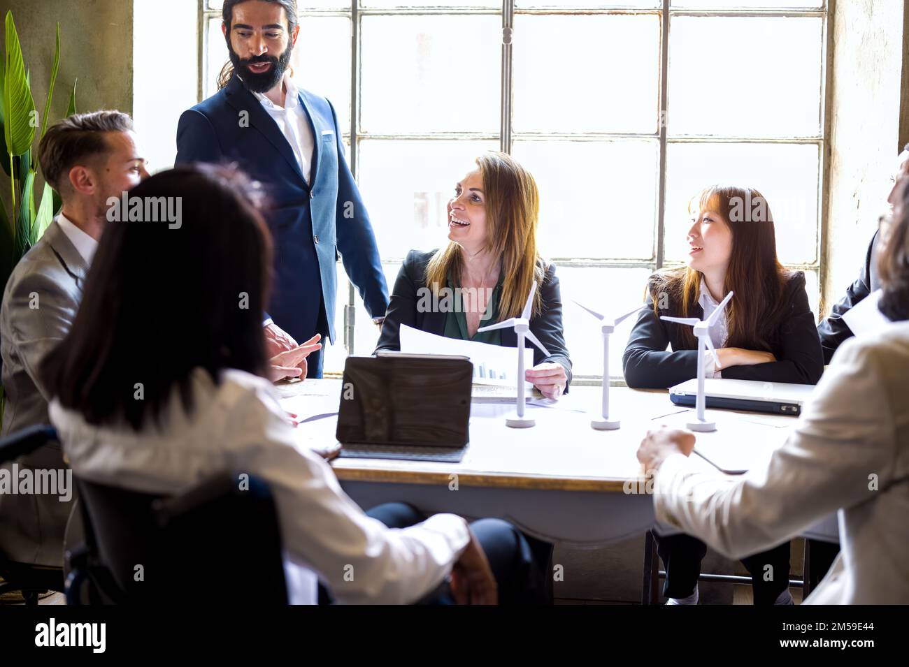 Gruppo di imprenditori multietnici che lavorano a un progetto di energia rinnovabile sostenibile, donna sorridente felice e fiduciosa su focus, vintage building off Foto Stock