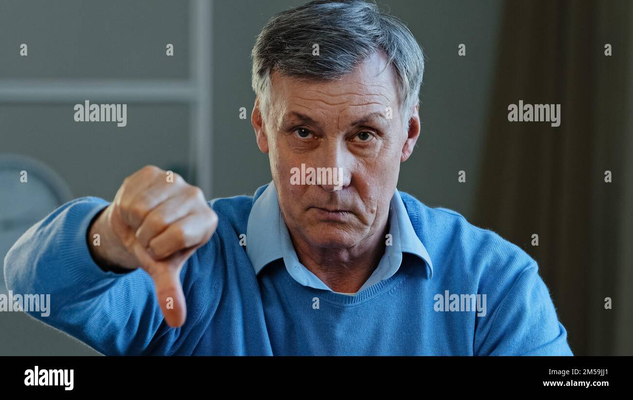 Ritratto di arrabbiato triste uomo anziano che guarda la macchina fotografica scontento grave vecchio nonno maturo mostrando dispiacere pollici verso il basso atteggiamento negativo Foto Stock