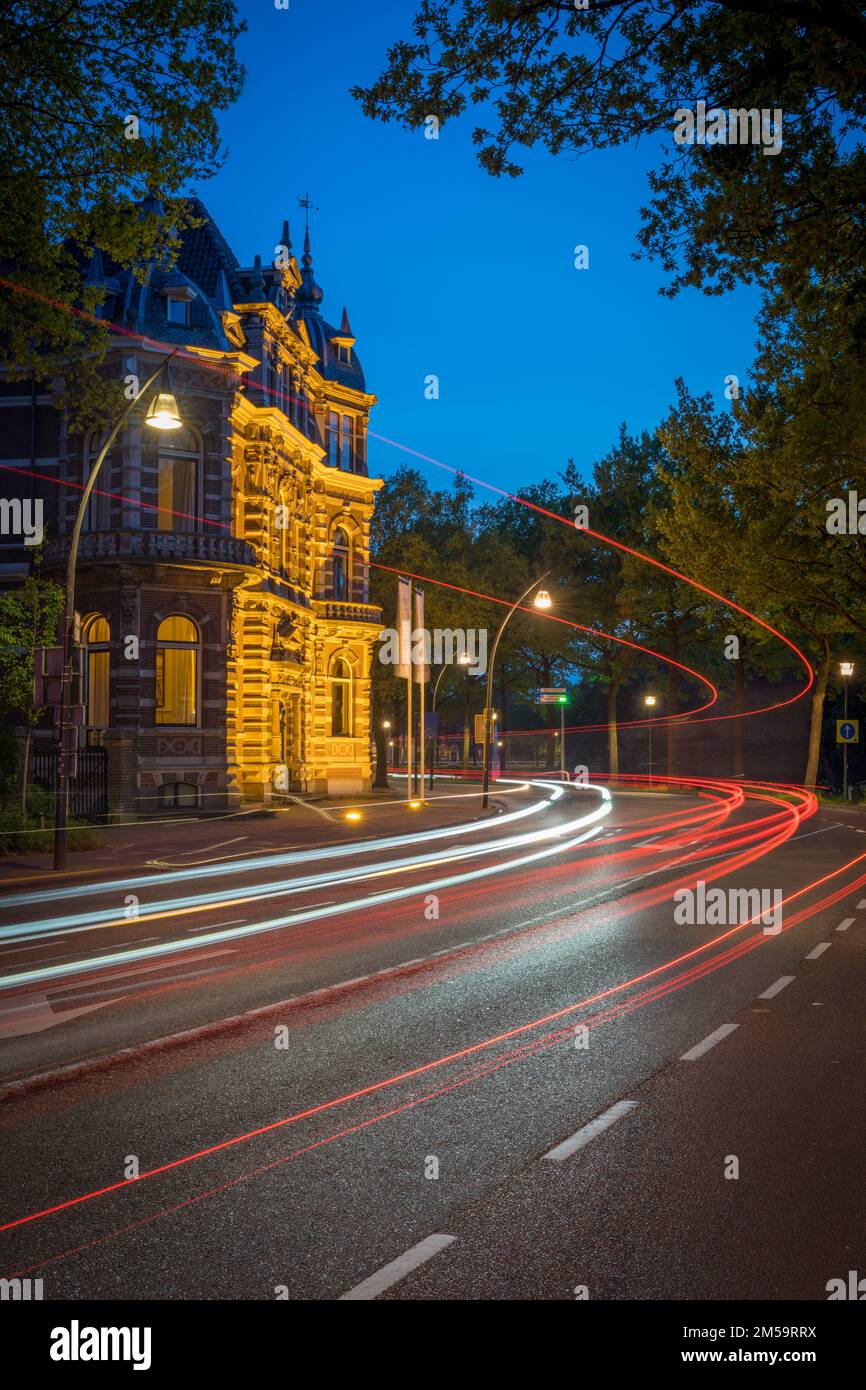 Un movimento verticale sfocato di una strada autostradale con un antico edificio sul lato di notte Foto Stock