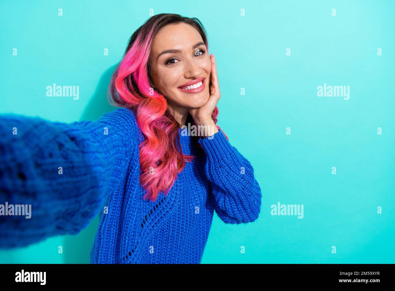 Primo piano selfie foto cadre di giovane affascinante ragazza hipster indossare blu maglia jumper touch guancia prendere shot guardare si isolato su sfondo di colore ciano Foto Stock