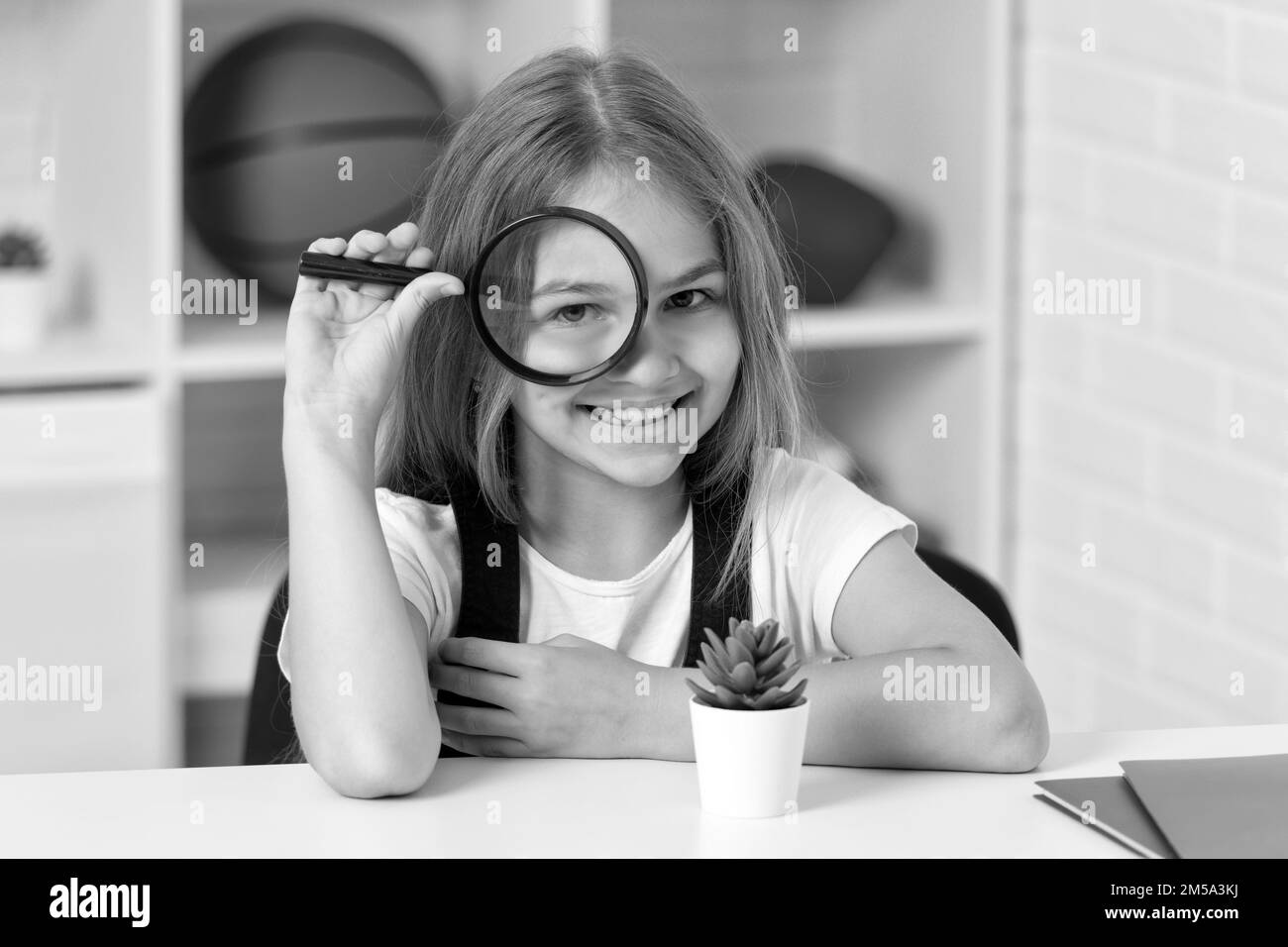 indagare con lupe. scienza e infanzia. ragazza teen guardando pianta attraverso lente di ingrandimento Foto Stock