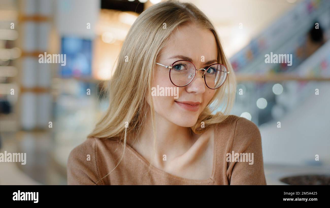 Primo piano emotivo sorridente flirting caucasico 20s donna in occhiali donna ragazza bionda donna in occhiali indoor posa guardando la macchina fotografica Foto Stock