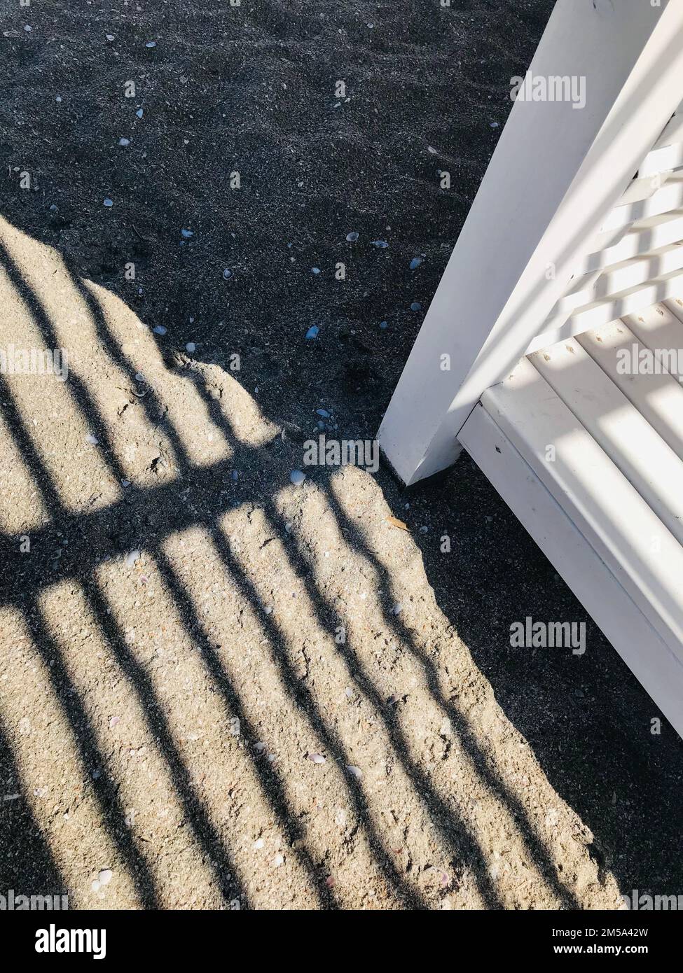 Le ombre si stacchano nella sabbia da un baldacchino di legno sulla spiaggia. Immagine di sfondo estiva. Foto Stock