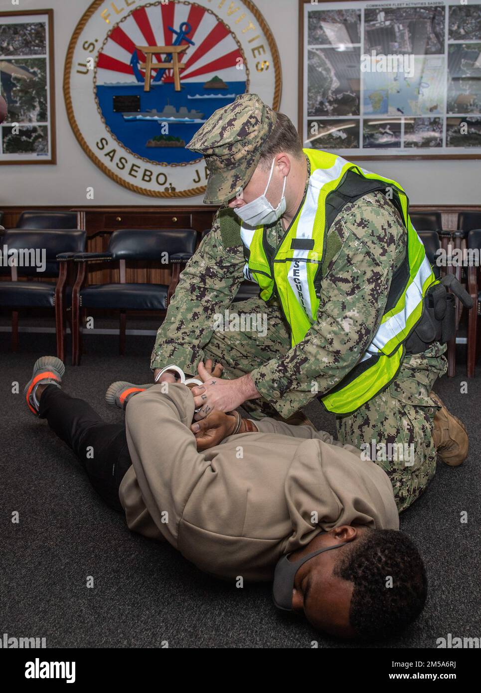 Master-at-Arms 2nd Class Bradley Canada, assegnato a Commander, Fleet Activities Sasebo (CFAS) manette Master-at-Arms 1st Class Fredrick Cuffy che ha agito come uno sparatutto attivo simulato durante un esercizio di punta attivo al CFAS 15 febbraio 2022. Per 75 anni, CFAS ha fornito, mantenuto e gestito strutture e servizi di base per potenziare le forze alleate e statunitensi schierate in futuro, fornendo al contempo un supporto superiore alle loro famiglie e alla comunità. Foto Stock