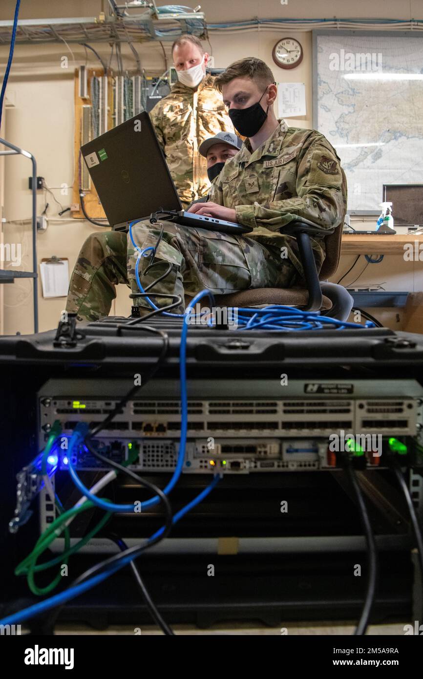 STATI UNITI Jake Spuller, a sinistra, il comandante di volo delle missioni speciali dello Squadrone delle comunicazioni aeree 611th; Brandon Baldwin, al centro, 611th ACOMS Mission Defense Team System Administrator; E il Senior Airman Samuel Ackerman, a destra, un operatore del team ACOMS Mission Defense 611th, eseguono misure di sicurezza informatica in un sito radar a lungo raggio a Utqiagvik, Alaska, 15 febbraio 2022. L'ACOMS 611th ha visitato l'LRRS per convalidare l'integrità dei dati ricevuti dal sito. Foto Stock