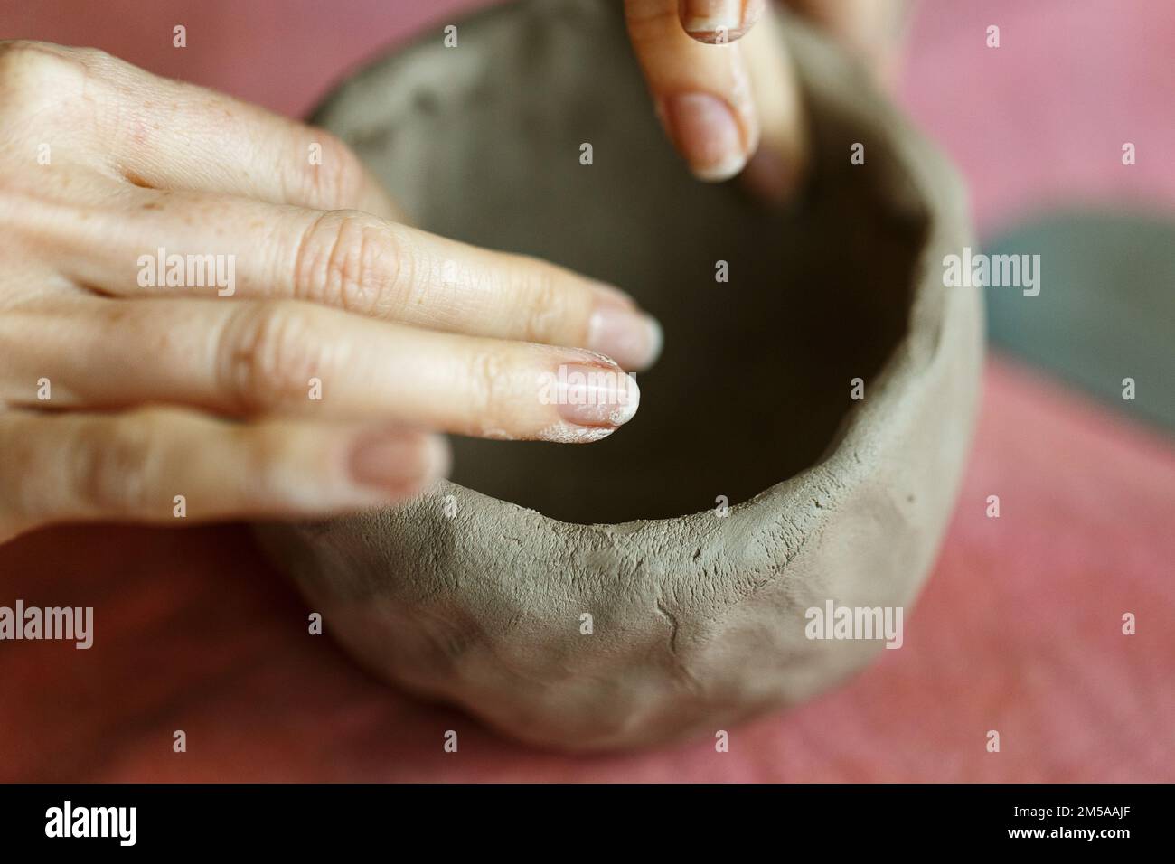 Le mani delle donne impastano l'argilla e scolpiscono una tazza da essa. Il processo di fabbricazione di un prodotto ceramico,primo piano. Foto Stock