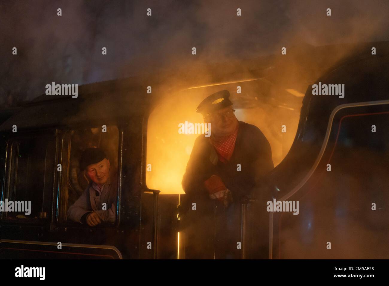 Allenatore di una locomotiva a vapore che guarda fuori dalla cabina su una nuvola di vapore Foto Stock