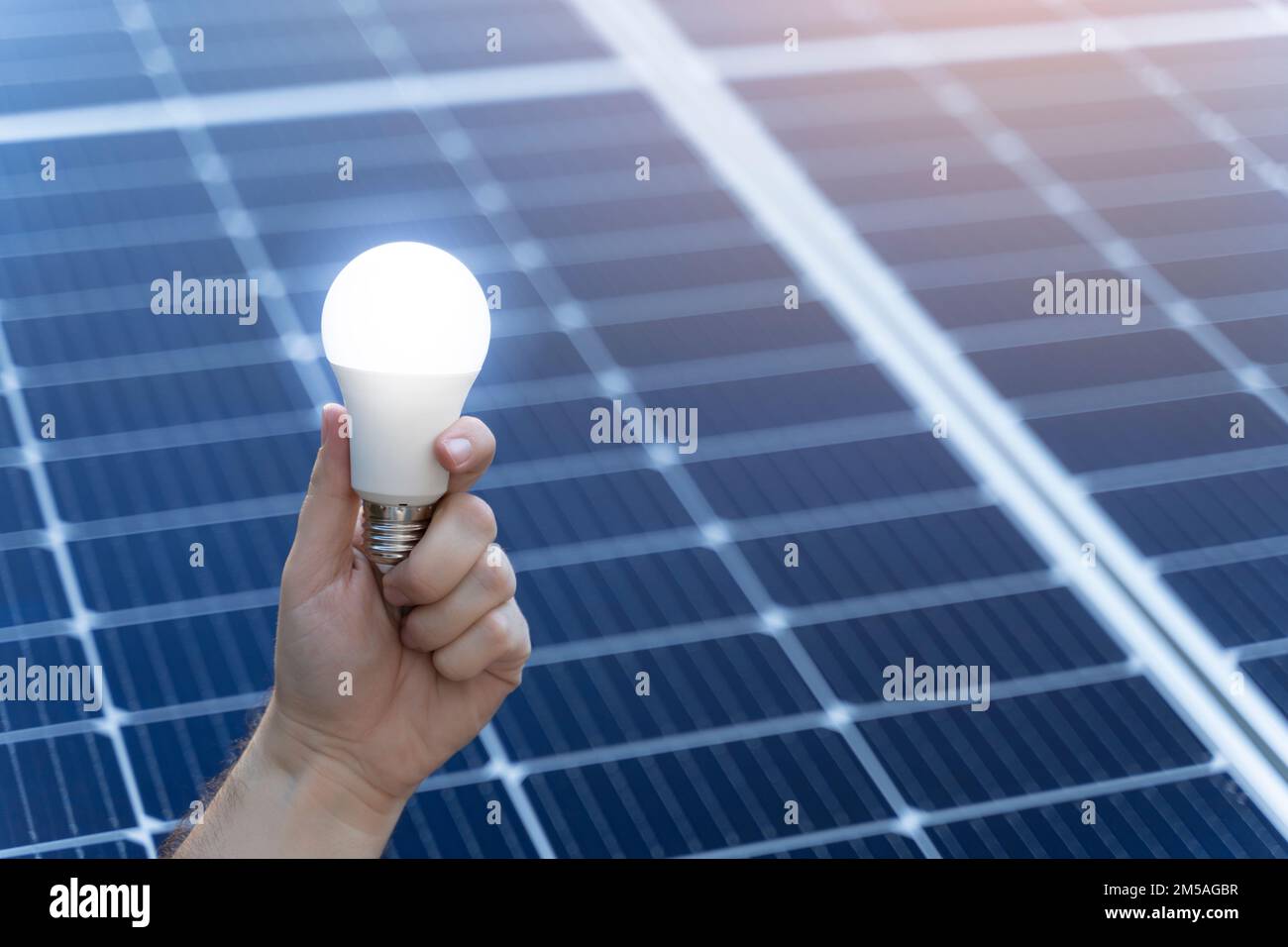 Concetto di risparmio energetico con lampadina e pannelli solari Foto Stock