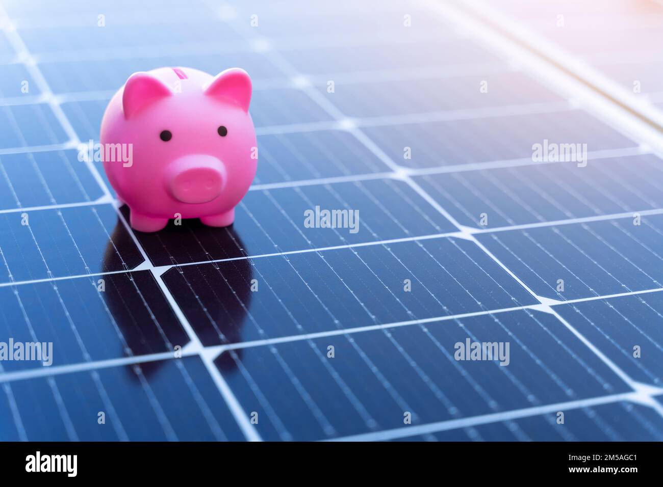 Concetto di risparmio energetico con pannelli solari e un banco di porcellini Foto Stock