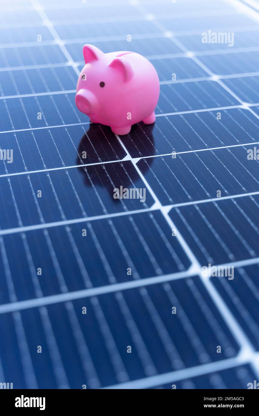 Concetto di risparmio energetico con pannelli solari e un banco di porcellini Foto Stock