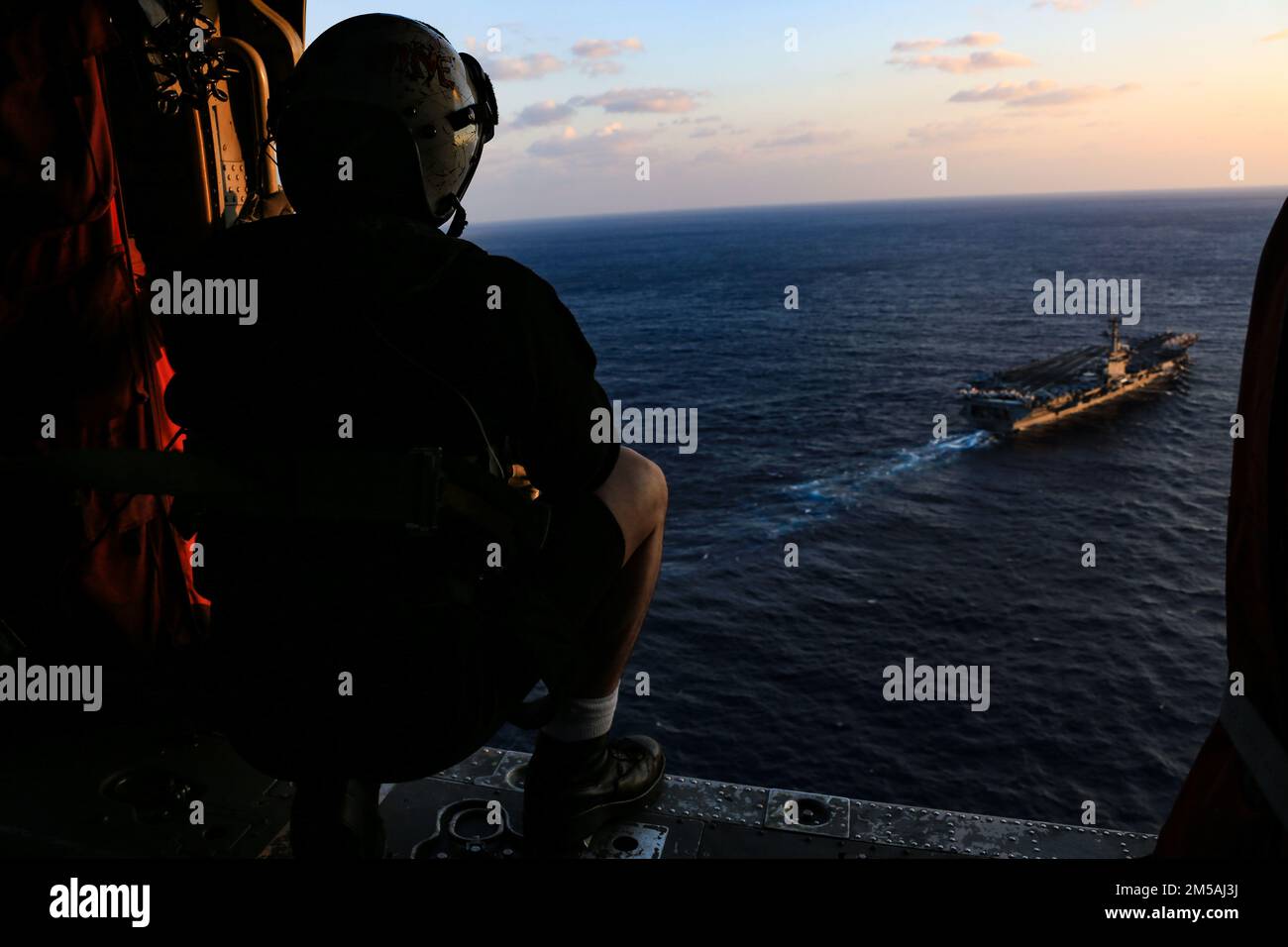 MAR DELLE FILIPPINE (Feb 16, 2022) U.S. Navy Naval Aircrewman (elicottero) 3rd Classe Noah Vigileos, di Tucson, Ariz., osserva la portaerei di classe Nimitz USS Abraham Lincoln (CVN 72), la nave da crociera missilistica guidata di classe Ticonderoga USS Mobile Bay (CG 53) e la cacciatorpediniera missilistica guidata di classe Arleigh Burke USS Spruance (DDG 111) Naviga in formazione con la Japan Maritime Self-Defense Force (JMSDF) cacciatorpediniere di classe Murasame JS Inazuma (DD 105) e Hatakaze-classe JS Hatakaze (TV [nave da addestramento] 3520) durante l'esercizio Jungle Warfare 2022 (JWX 22) dalla cabina di un elicottero MH-60s Sea Hawk, assegnato a. Foto Stock