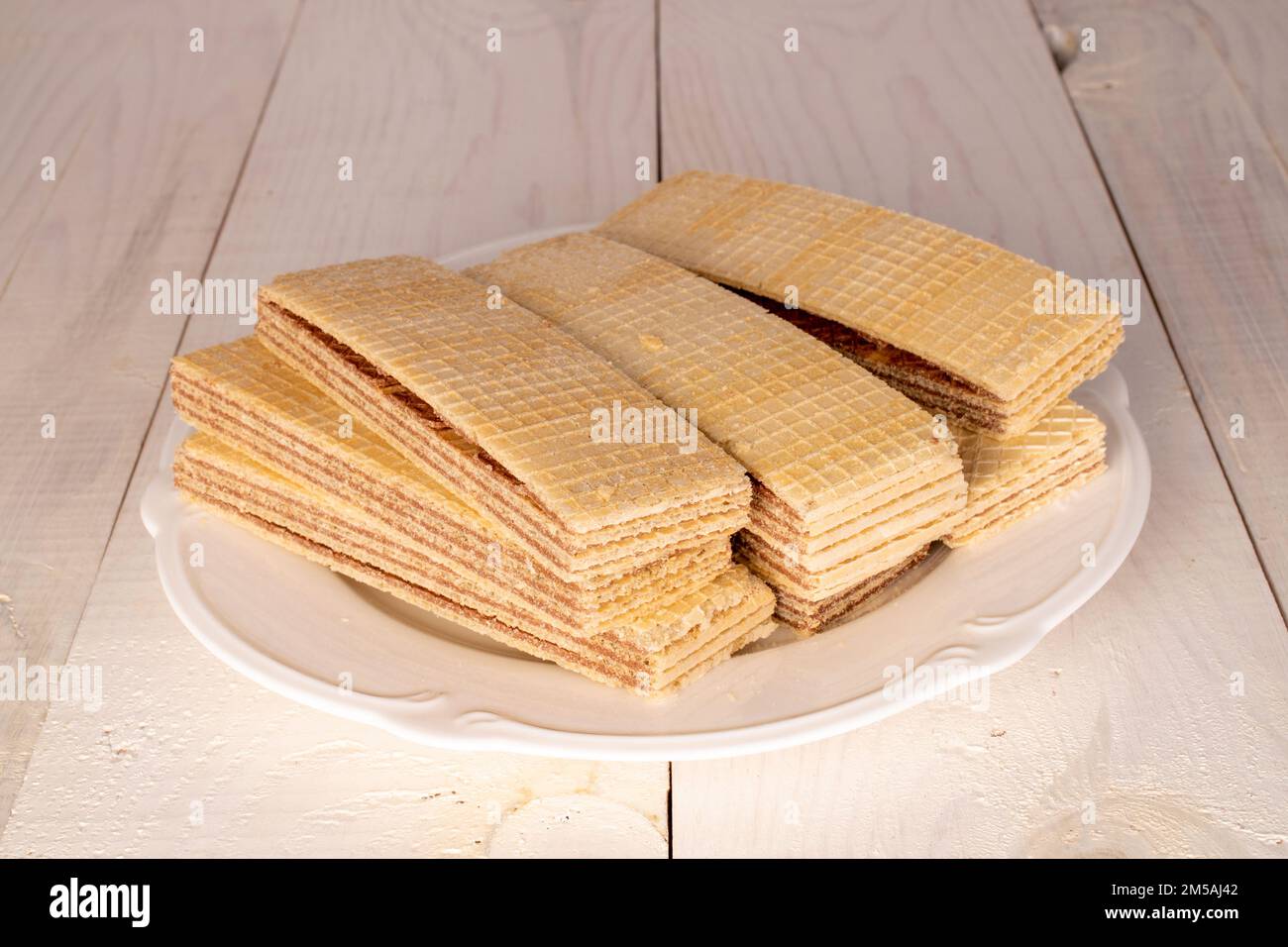 Diversi wafer di cioccolato dolce con piatto bianco su tavolo di legno, primo piano. Foto Stock