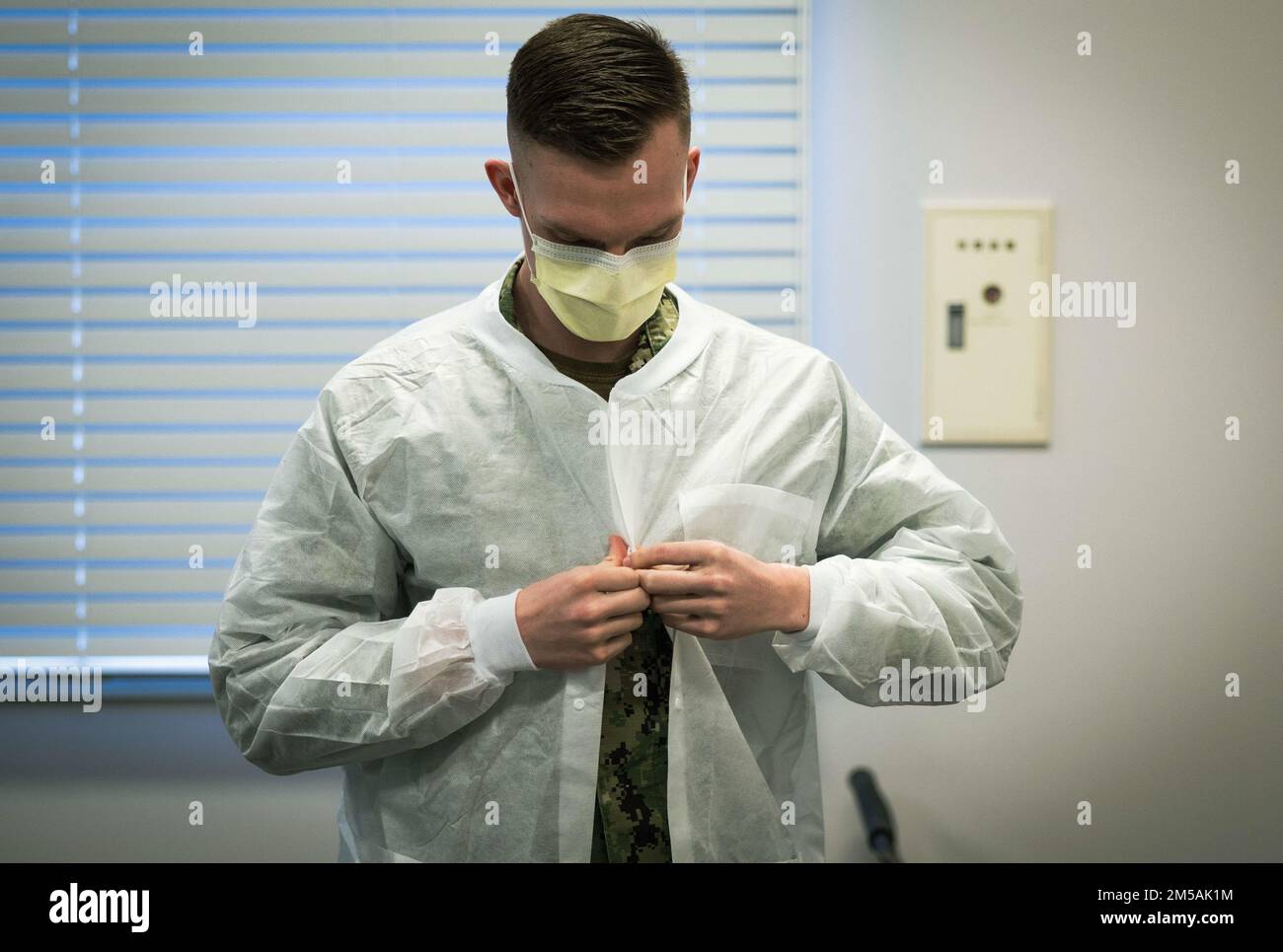 STATI UNITI Navy Seaman Caleb Werner, un membro del team mobile del programma Armed Services Blood Program, si mette su un camice da laboratorio durante un viaggio di sangue a Camp Foster, Okinawa, Giappone, 16 febbraio 2022. L'ASBP è il fornitore militare ufficiale di sangue per servire membri, veterani e famiglie militari. L'ASBP ospita corse di sangue ogni martedì al cinema Camp Foster dalle 7:11 alle 24:00 Foto Stock