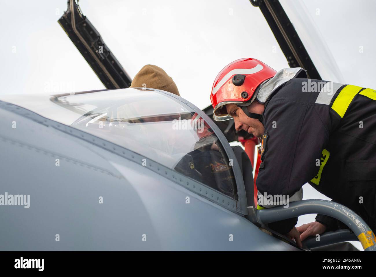 SRA Joshua Stokes, un Journeyman di recupero di scontro, assegnato al 48th ° Squadrone di ingegneria civile dalla 48th Fighter Wing, Royal Air Force (RAF) Lakenheath, Inghilterra, spiega la procedura di uscita su un F-15C Eagle anche assegnato a RAF Lakenheath, a privati di prima classe Orlok Grzegorz, Un pompiere polacco assegnato alla base aerea tattica 32nd, Łask base aerea Polonia, febbraio 16. 2022. Le forze statunitensi si allenano regolarmente con le nazioni alleate e partner per garantire la capacità, la forza e l'impegno di tali partnership per scoraggiare e difendere contro gli avversari emergenti. Foto Stock