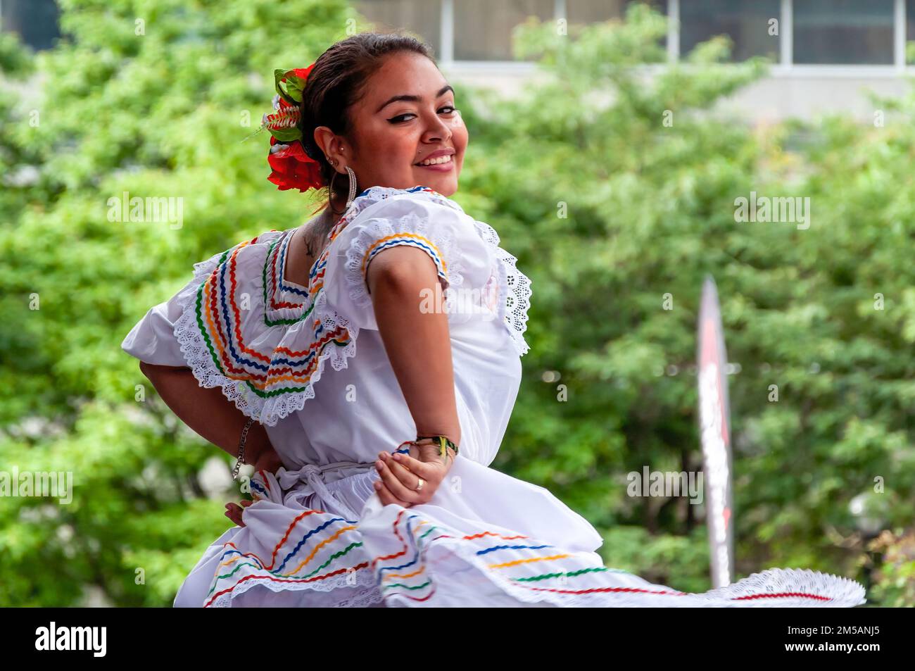 Una donna sorridente indossa abiti tradizionali latinoamericani mentre balla sul palco. L'evento annuale si svolge in piazza Mel Lastman. Foto Stock