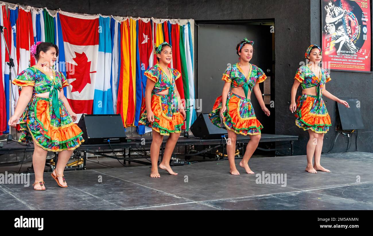 Un gruppo di bambini che indossano abiti tradizionali latinoamericani ballano sul palco. L'evento annuale si svolge in piazza Mel Lastman. Foto Stock