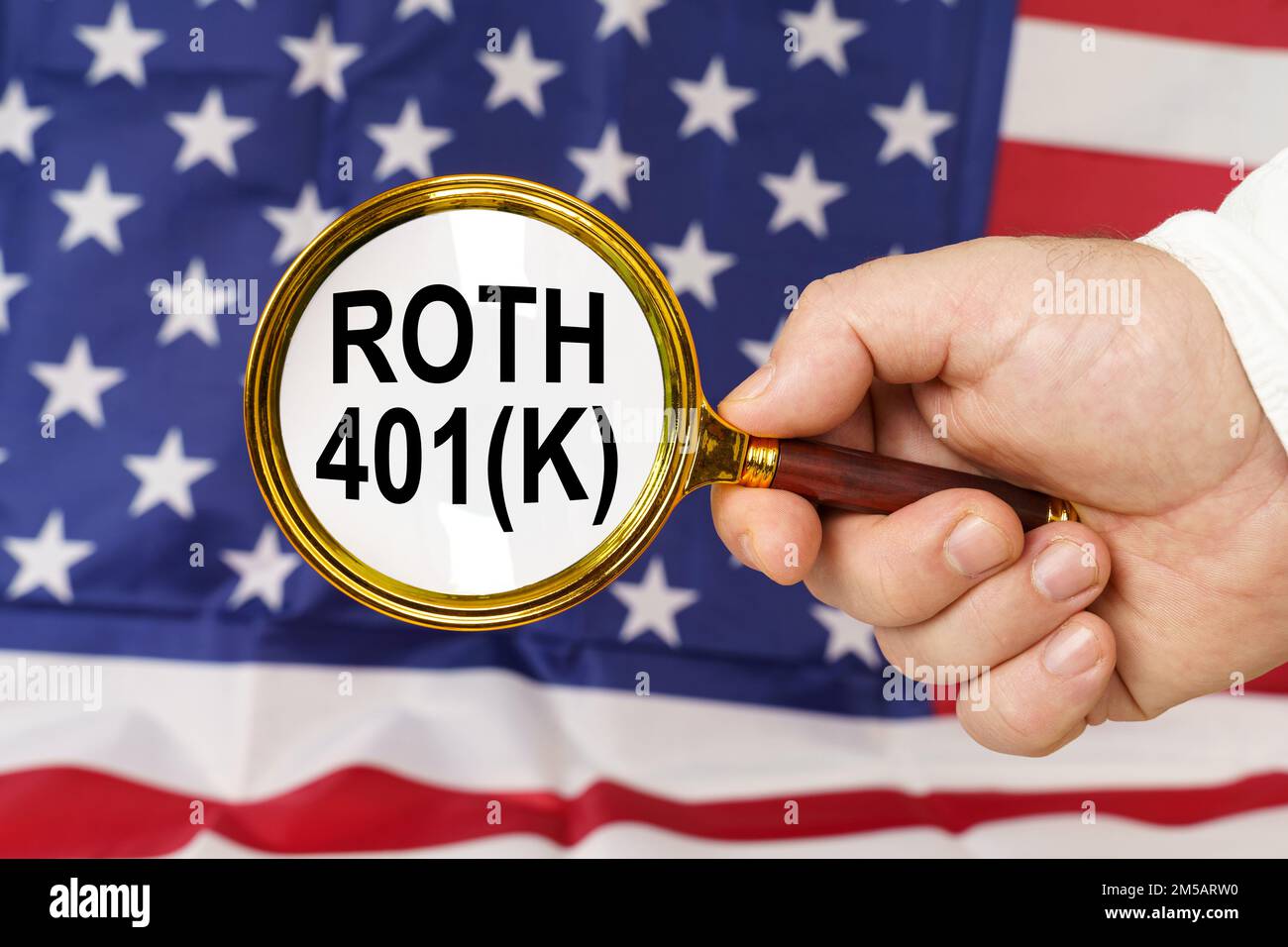 Davanti alla bandiera americana, un uomo tiene in mano una lente d'ingrandimento con l'iscrizione Roth 401k. Foto Stock