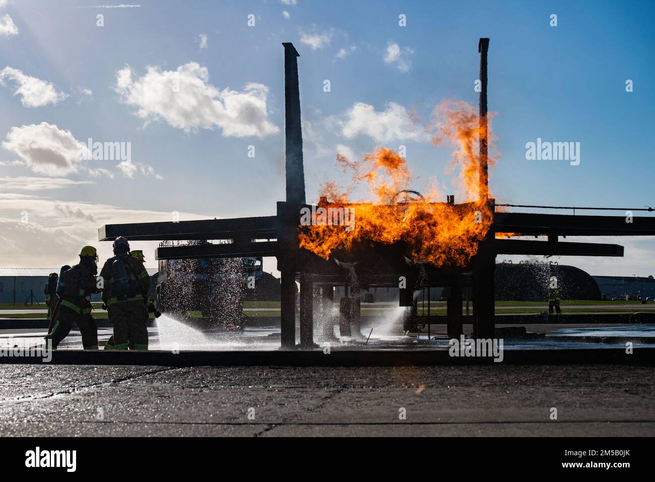 I vigili del fuoco dello Squadron, ingegnere civile del 48th, si muovono per spegnere un incendio del motore durante un esercizio di masterizzazione simulato dell'aeromobile presso Royal Air Force Lakenheath, Inghilterra, 17 febbraio 2022. La fossa di scottatura di velivolo di mock fornisce addestramento realistico per i vigili del fuoco con le fiamme tecnicamente controllate che emanano dalle varie zone di un telaio metallico di velivolo. Foto Stock