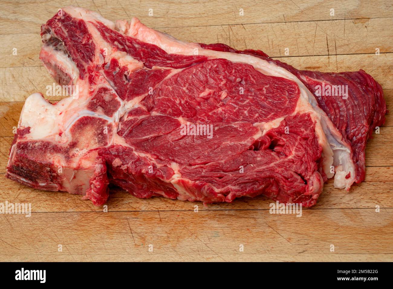 Alimenti ad alto contenuto proteico, carni rosse sane e dieta carnivore concetto con grande mandrino di carne magra muscolare e ossa su legno rustico tagliere bordo Foto Stock