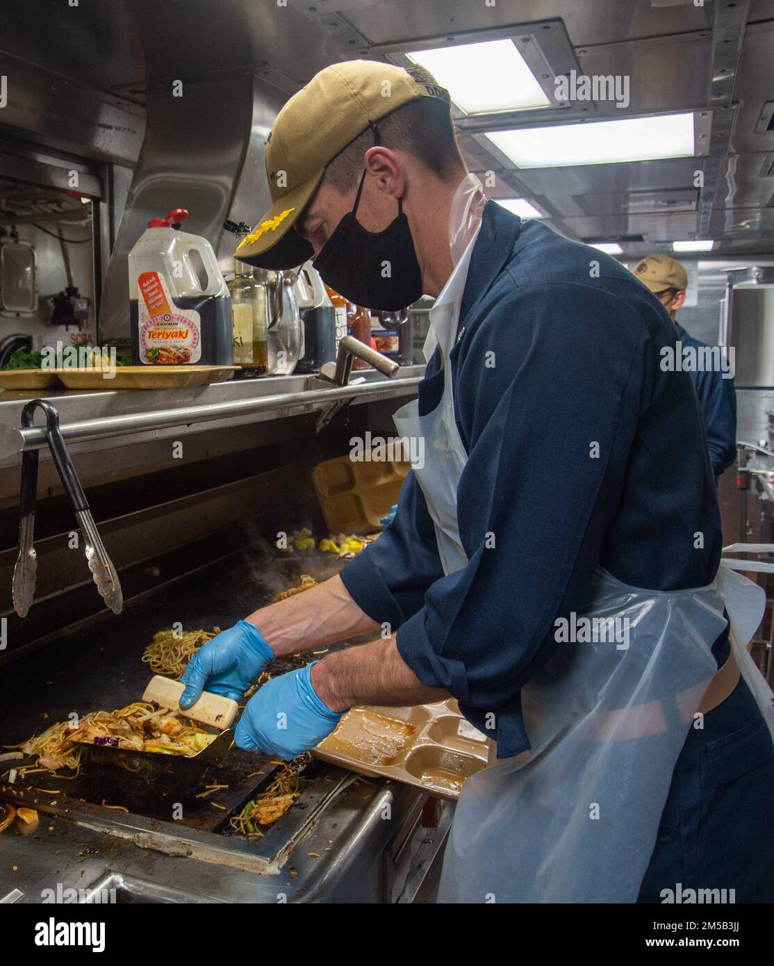 220217-N-EH998-1074 OCEANO ATLANTICO (17,2022 febbraio) CMdR. Tom Roberts, ufficiale esecutivo del cacciatorpediniere missilistico guidato USS Farragut (DDG 99), serve barbecue mongolo durante il pranzo mentre è in corso per Surface Warfare Advanced Tactical Training (SWATT). Farragut fa parte di Destroyer Squadron (DESRON) 26 che supporta Carrier Strike Group (CSG) 10. SWATT è guidata dal Naval Surface and Mine Warfighting Development Center (SMWDC) ed è progettata per aumentare la competenza, la letalità e l'interoperabilità delle unità partecipanti. Foto Stock