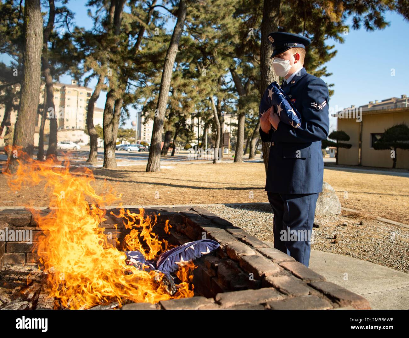 Airman First Class Anthony Paree, 8th Fighter Wing base Honor Guardsman, detiene una bandiera americana ritirata prima di mettere in un cerimonioso fuoco alla base aerea di Kunsan, Repubblica di Corea, 18 febbraio 2022. Quando una bandiera americana è ritenuta non più riparabile, deve essere onorata con una cerimonia di pensione e bruciata. Foto Stock