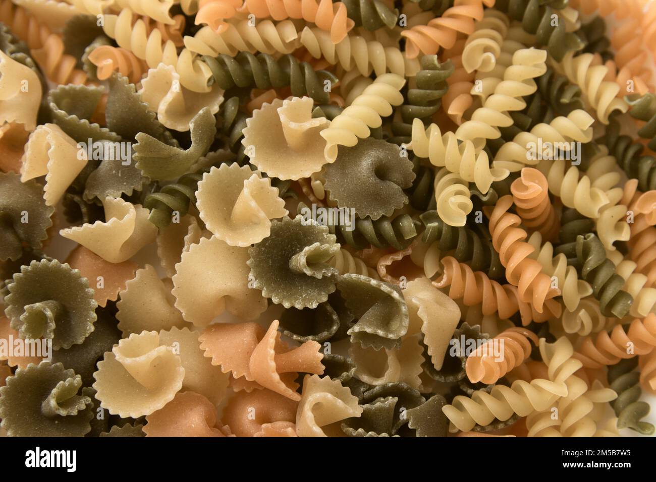 Primo piano di un piatto con pasta corta di vari colori e forme come fusilli e margherite Foto Stock