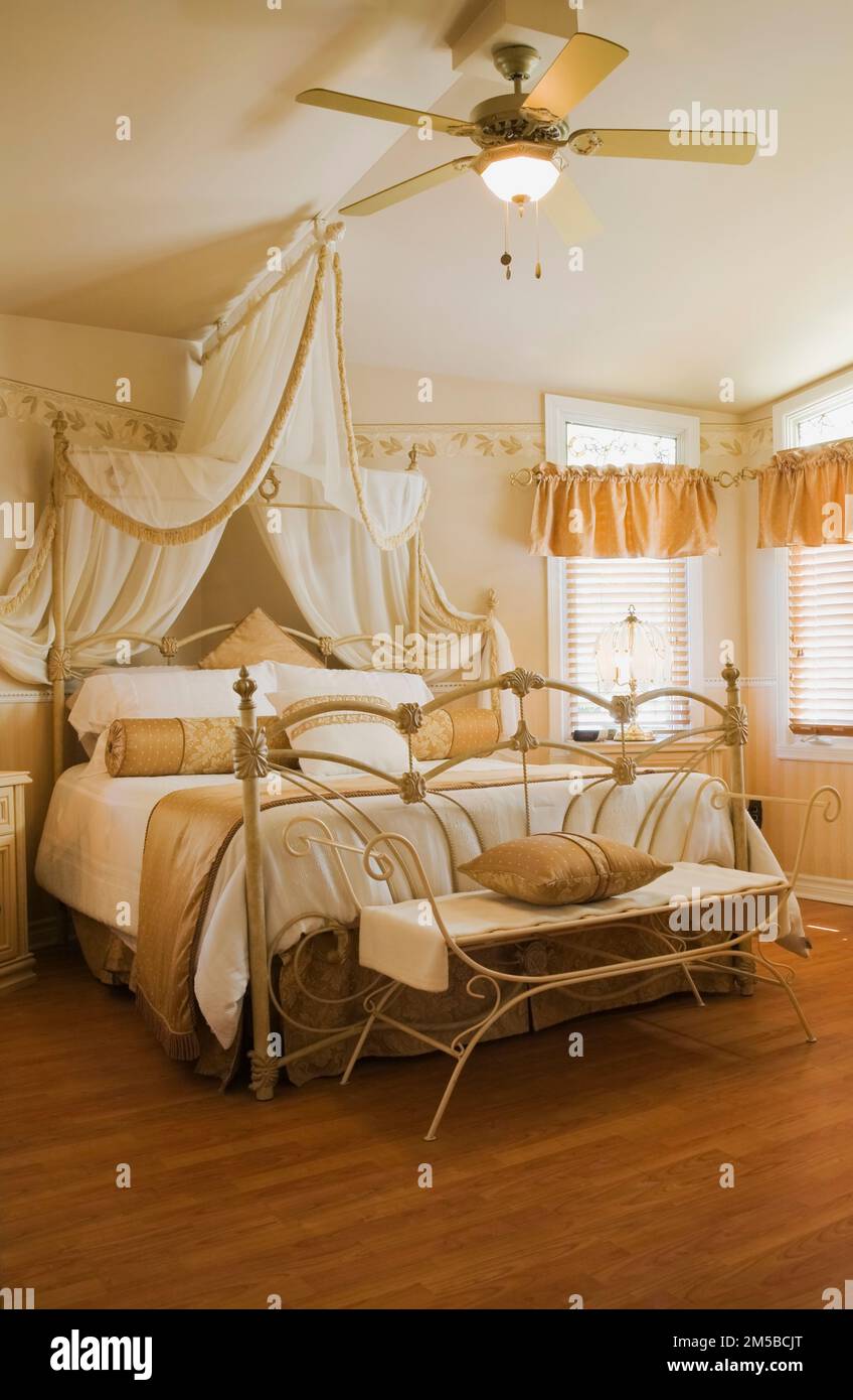Antico letto queen size a baldacchino con testata in ferro battuto e pedane nella camera da letto principale all'interno di 1987 Archimed stile casa. Foto Stock