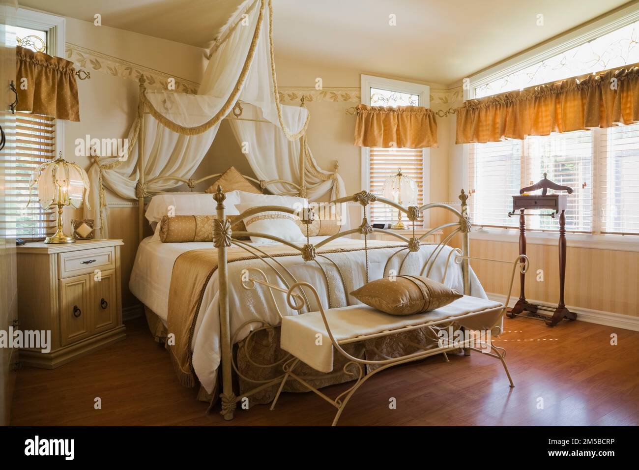 Antico letto queen size a baldacchino con testata in ferro battuto e pedane nella camera da letto principale all'interno di 1987 Archimed stile casa. Foto Stock