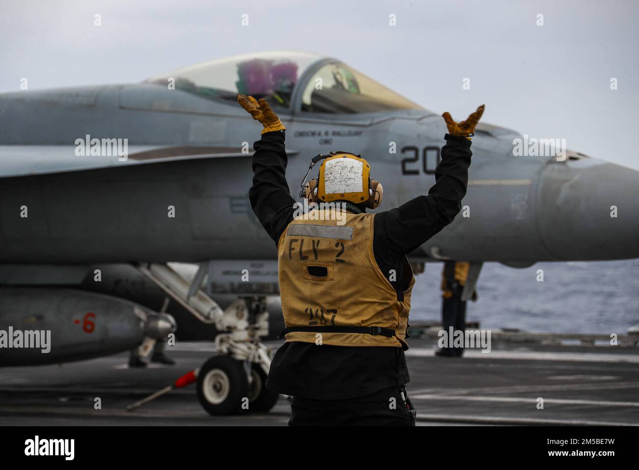 PHILIPPINE SEA (21 febbraio 2022) Aviation Boatswain's Mate (Handling) 2nd Class Devin Reynoso, di Port Hueneme, California, dirige un F/A-18E Super Hornet, assegnato ai 'Tophatters' di Strike Fighter Squadron (VFA) 14, sul ponte di volo del portaerei di classe Nimitz USS Abraham Lincoln (CVN 72). Abraham Lincoln Strike Group è in fase di implementazione pianificata nell'area delle operazioni della flotta 7th degli Stati Uniti per migliorare l'interoperabilità attraverso alleanze e partnership e al tempo stesso fungere da forza di risposta pronta a sostegno di una regione indomPacifico libera e aperta. Foto Stock