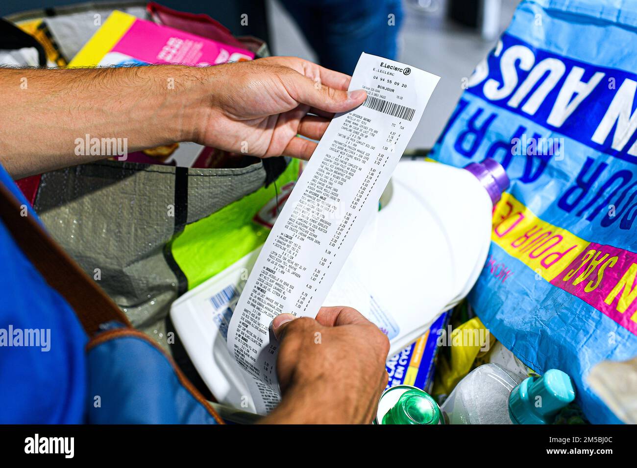 L'illustrazione mostra che un cliente che controlla la ricevuta cartacea del suo cassiere esce da un supermercato E.Leclerc (o Leclerc) a Cogolin, Francia il 27 dicembre; Foto Stock