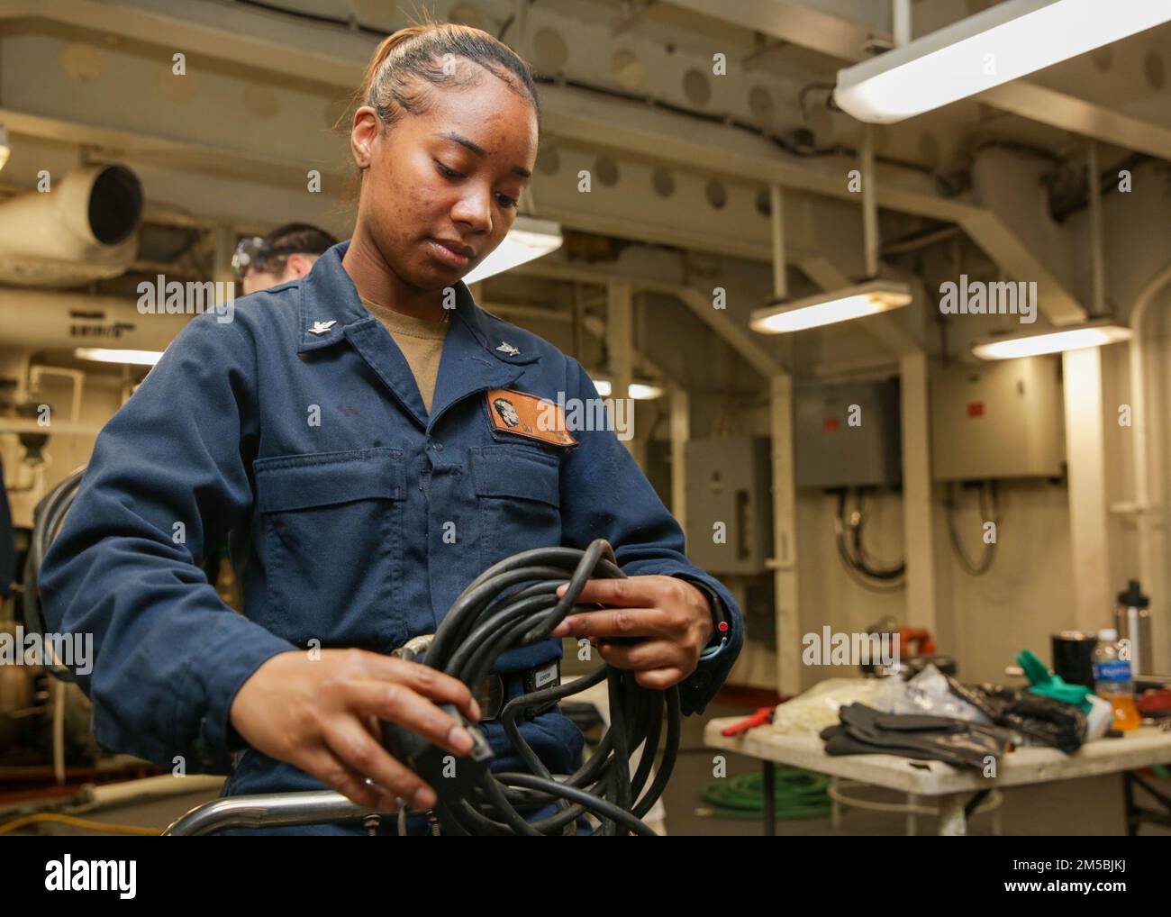 MARE DELLE FILIPPINE (23 febbraio 2022) il compagno di macchinisti 3rd Classe Lexus Gordon, di Norfolk, Virginia, avvolge una manichetta a lancia d'acqua a bordo della portaerei di classe Nimitz USS Abraham Lincoln (CVN 72). Abraham Lincoln Strike Group è in fase di implementazione pianificata nell'area delle operazioni della flotta 7th degli Stati Uniti per migliorare l'interoperabilità attraverso alleanze e partnership e al tempo stesso fungere da forza di risposta pronta a sostegno di una regione indomPacifico libera e aperta. Foto Stock